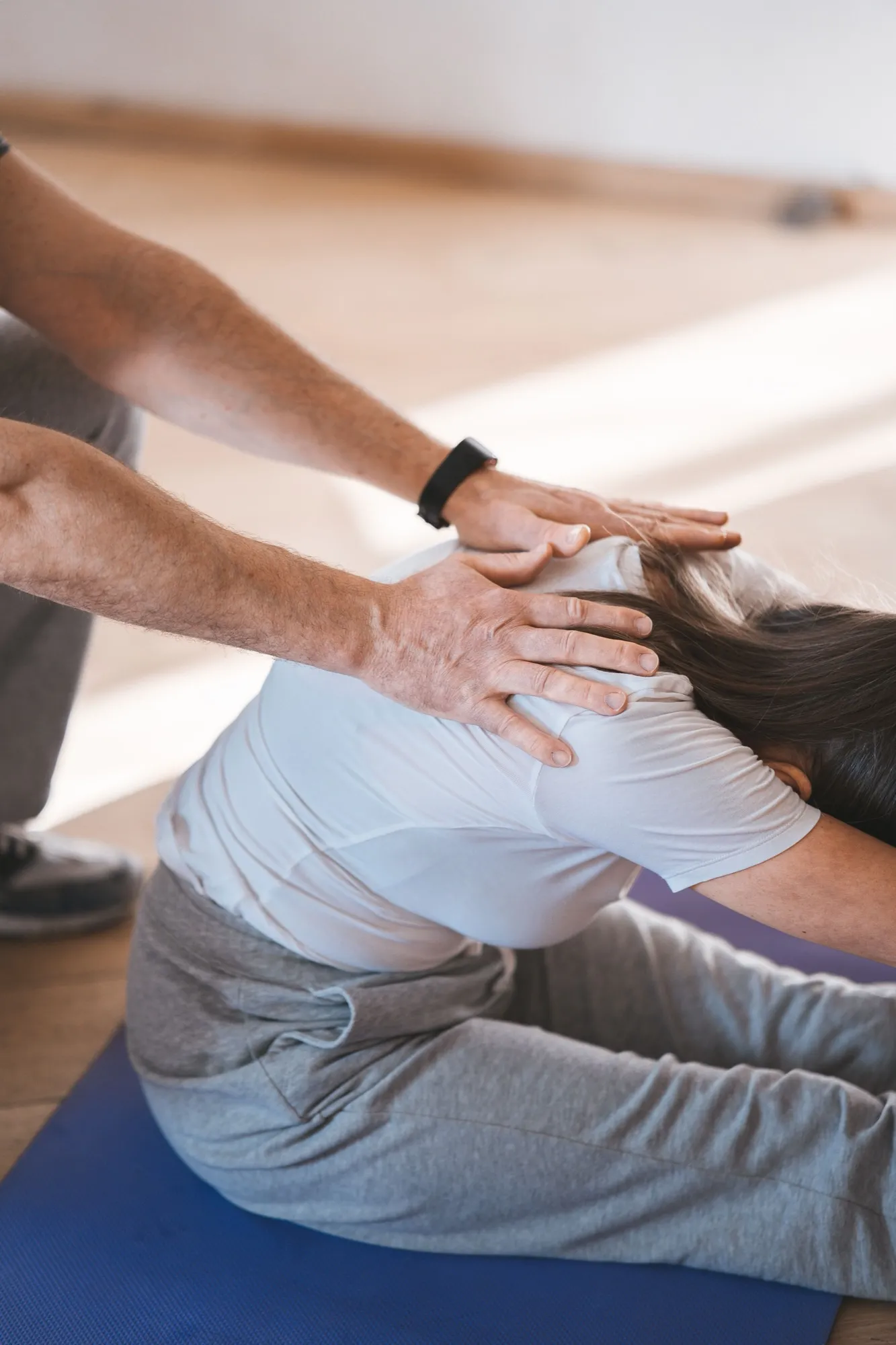 A physical therapist guiding a client through manual therapy on a mat